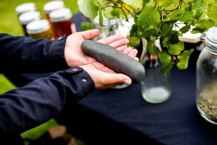 A close-up shot of a pair of hands holding a stone used in rongoā Māori traditional healing.